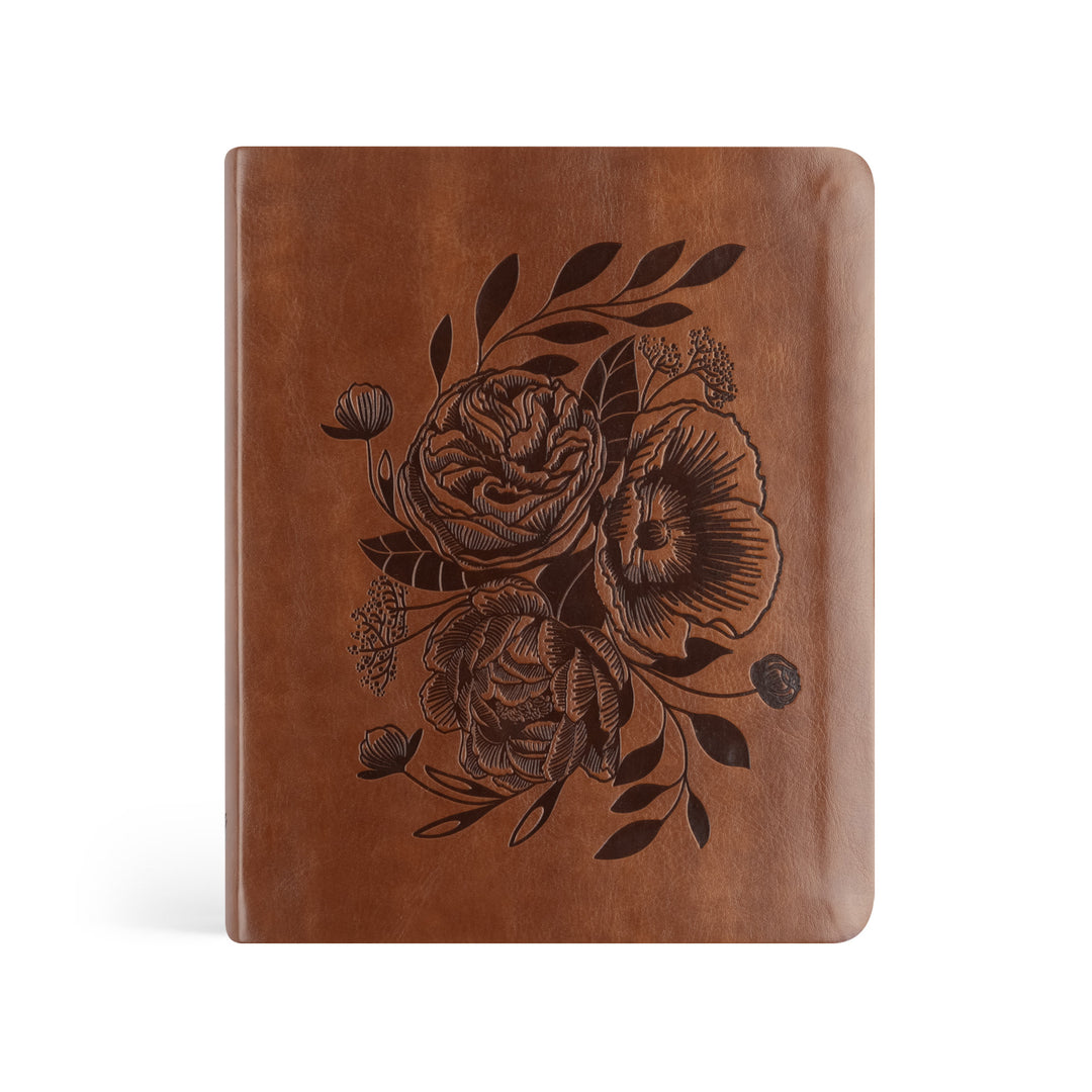 Brown leather notebook with floral embossing on a white background
