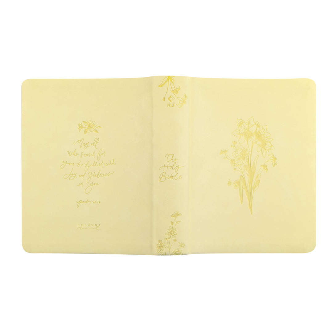 Open yellow Bible with floral designs and text on a white background
