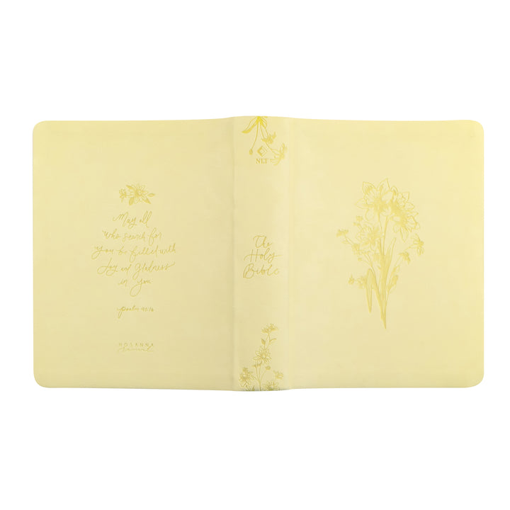 Open yellow Bible with floral designs and text on a white background
