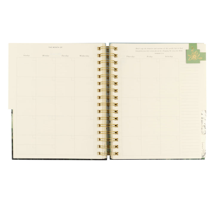 Open spiral-bound planner with gold binding on a white background