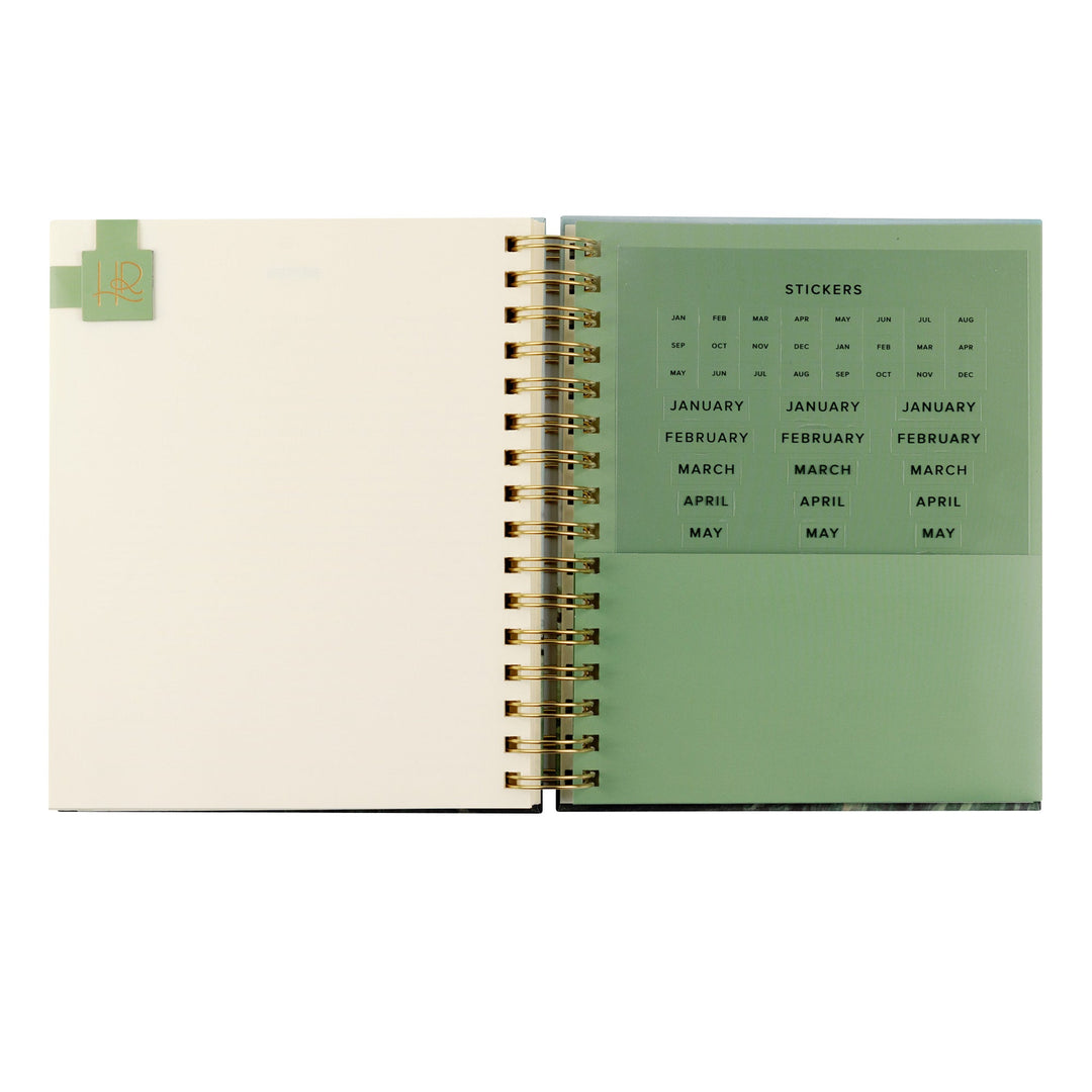 Open spiral-bound planner with green and beige pages on a white background