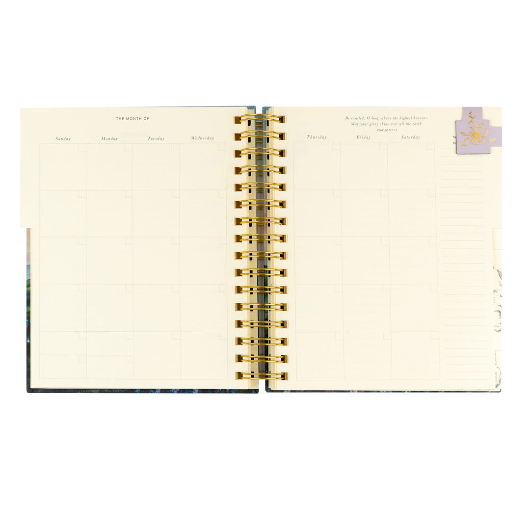 Open spiral-bound planner with gold binding on a white background