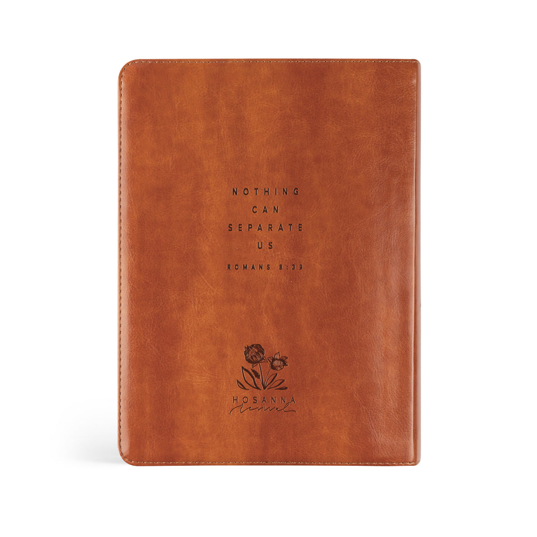 Brown leather notebook with embossed text and floral design on a white background