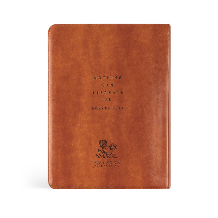 Brown leather notebook with embossed text and floral design on a white background