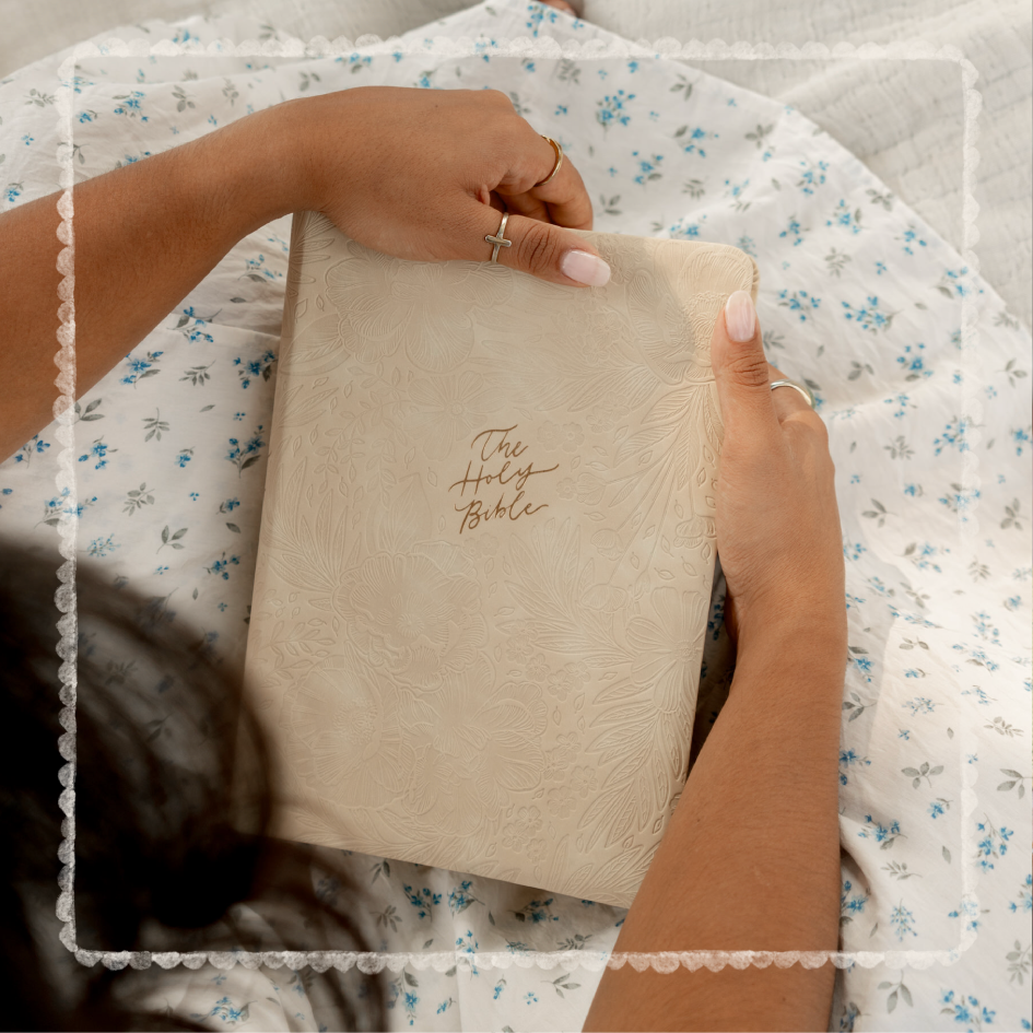 Person holding a beige Bible with floral leather background