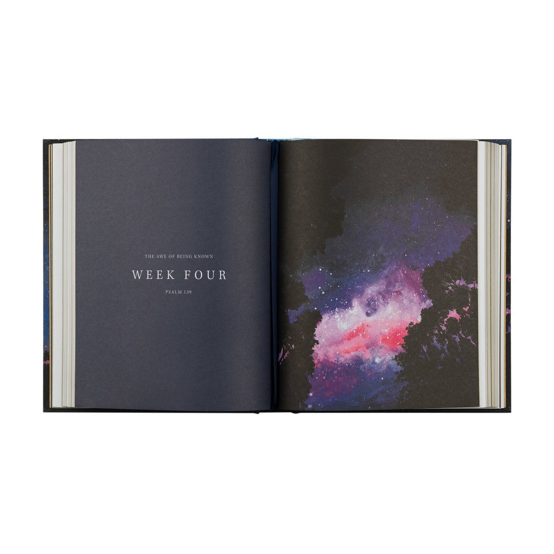 Open book showing a page with 'Week Four' text and another with a colorful nebula illustration.